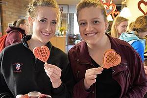 Two girls with heart shaped waffles at residence hall Valentine's day celebration